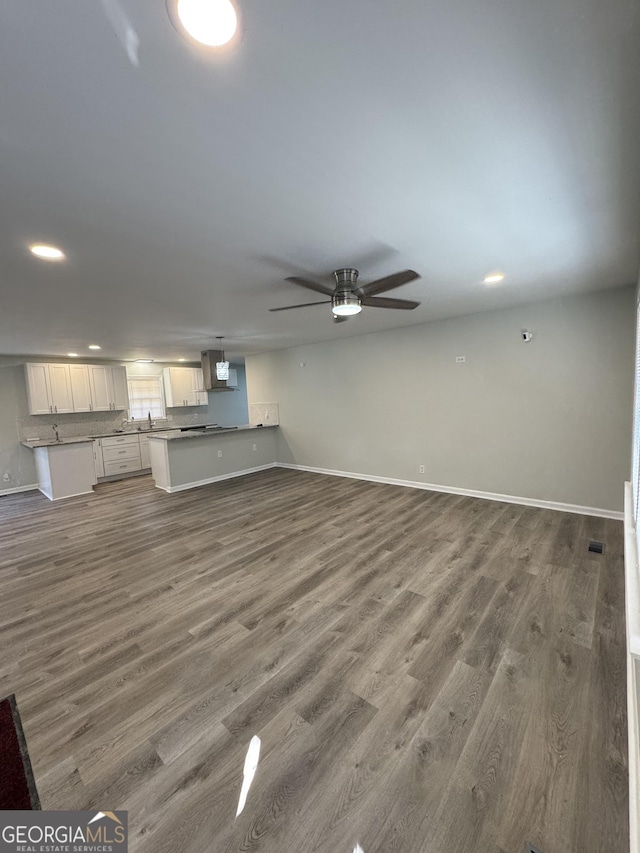 unfurnished living room featuring ceiling fan and wood-type flooring