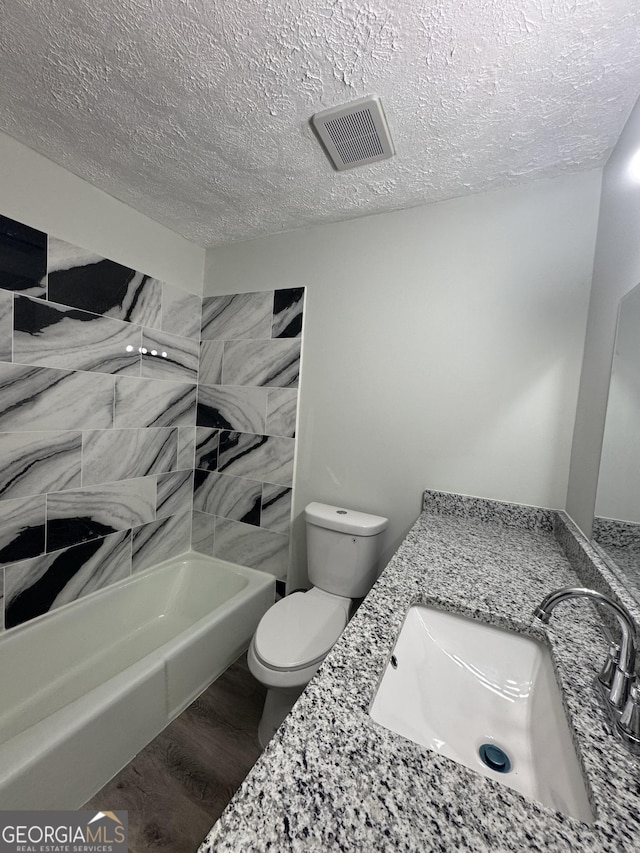 full bathroom with hardwood / wood-style floors, toilet, a textured ceiling, and bathing tub / shower combination