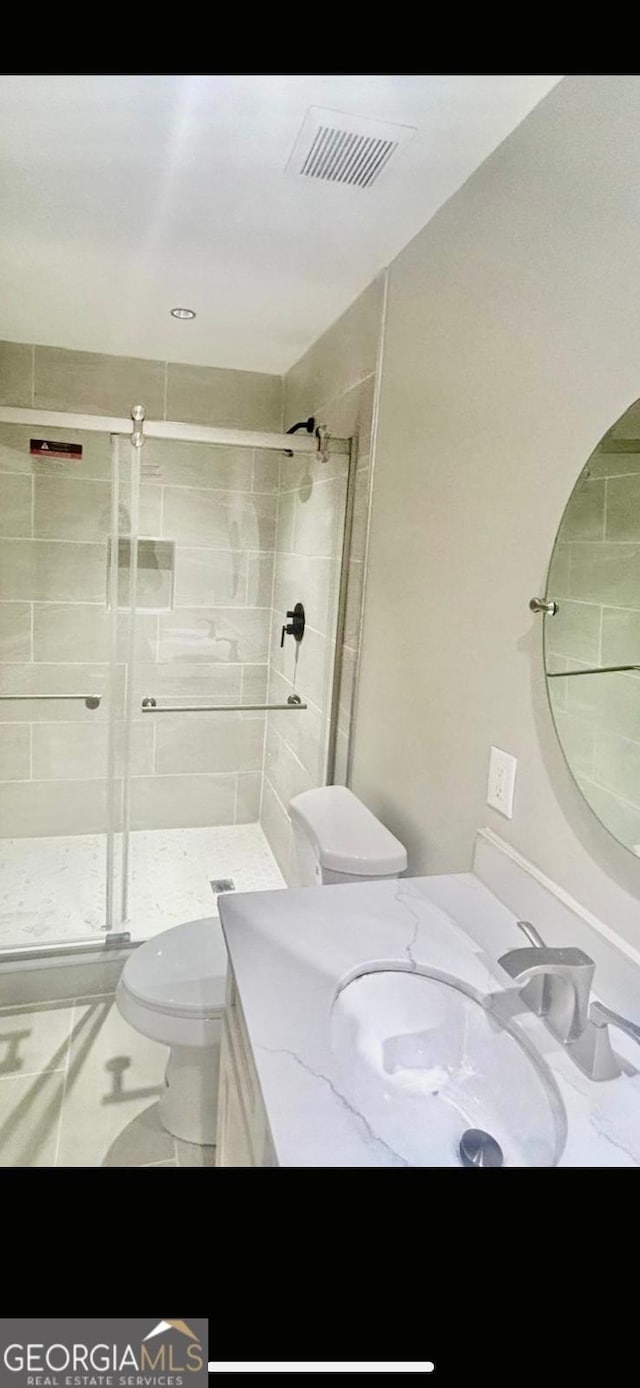 bathroom featuring tiled shower, vanity, and toilet