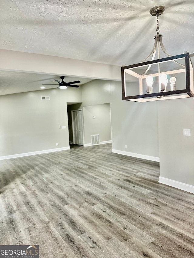 unfurnished living room with ceiling fan, a textured ceiling, and hardwood / wood-style flooring