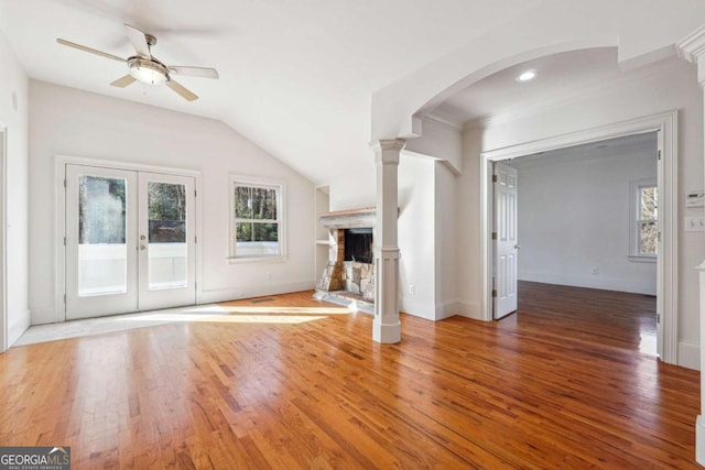 unfurnished living room with ceiling fan, wood-type flooring, decorative columns, and lofted ceiling