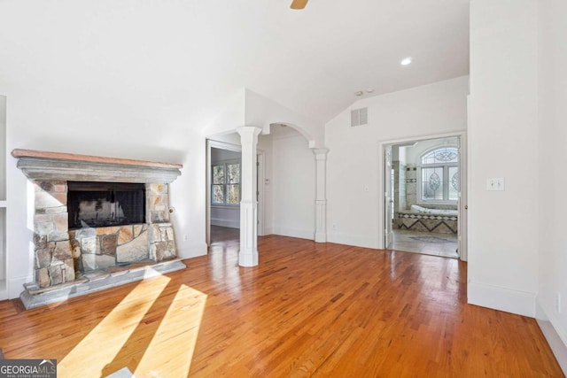 unfurnished living room featuring ornate columns, wood-type flooring, and a fireplace