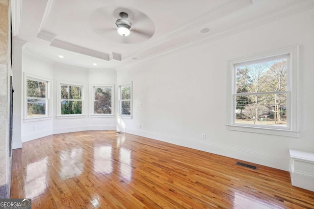 spare room with ceiling fan, ornamental molding, a raised ceiling, and light hardwood / wood-style floors