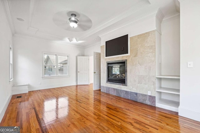 unfurnished living room with built in shelves, ornamental molding, hardwood / wood-style flooring, ceiling fan, and a fireplace