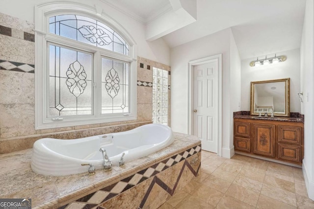 bathroom with tiled tub, vanity, and lofted ceiling