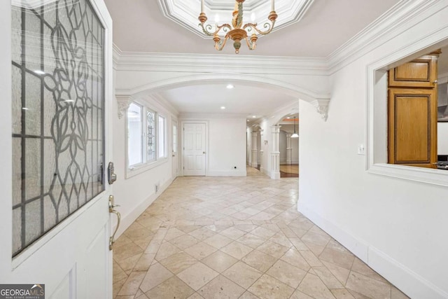 foyer with an inviting chandelier and ornamental molding