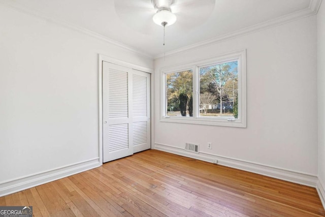 unfurnished bedroom featuring crown molding, ceiling fan, a closet, and light wood-type flooring