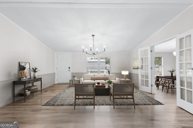 dining space with a chandelier, french doors, wood-type flooring, and vaulted ceiling