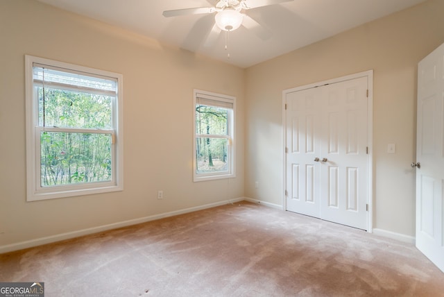 unfurnished bedroom featuring light carpet, multiple windows, a closet, and ceiling fan