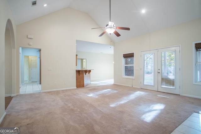 unfurnished living room with ceiling fan, light colored carpet, high vaulted ceiling, and french doors