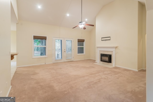 unfurnished living room featuring high vaulted ceiling, ceiling fan, light colored carpet, and a tile fireplace