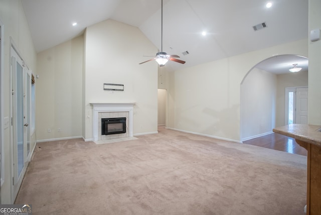 unfurnished living room with a tile fireplace, light carpet, ceiling fan, and lofted ceiling