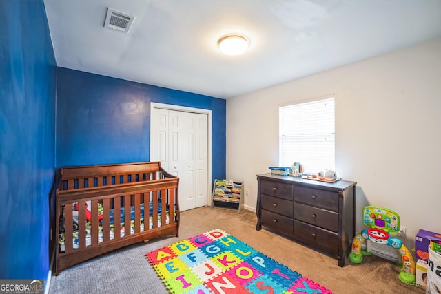 carpeted bedroom featuring a closet and a nursery area