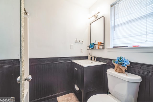 bathroom featuring vanity, toilet, and tile walls