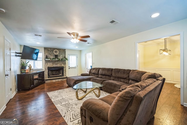 living room with ceiling fan, a fireplace, and dark wood-type flooring