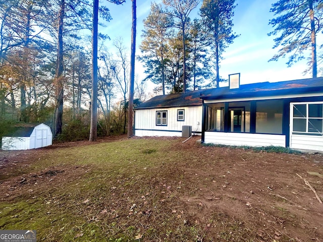 rear view of house featuring a yard, cooling unit, and a storage unit