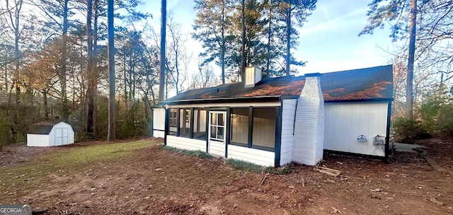 rear view of property with a storage shed and a sunroom