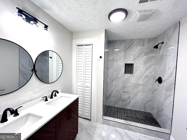 bathroom with vanity, a textured ceiling, and tiled shower