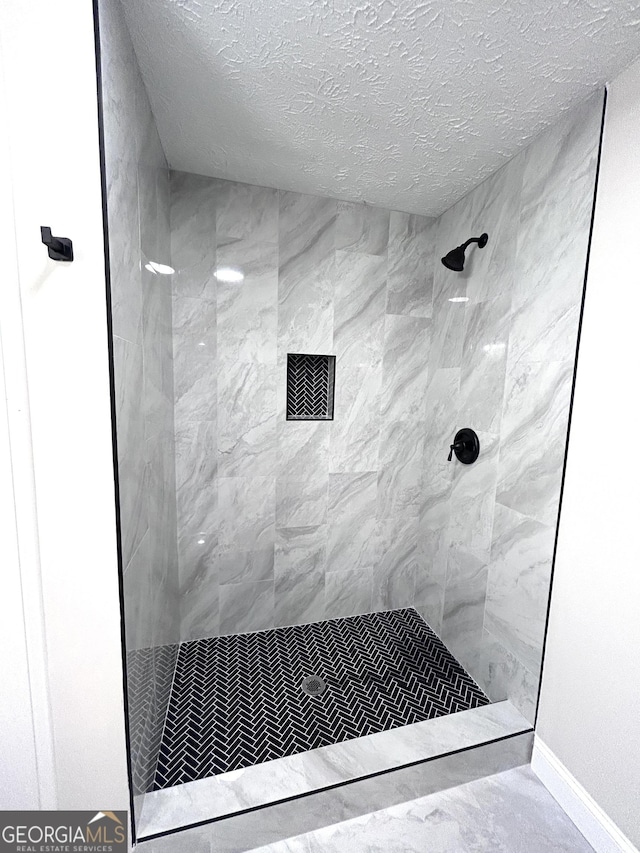 bathroom with a tile shower and a textured ceiling