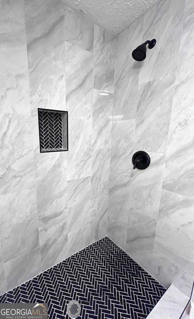 bathroom featuring tiled shower and a textured ceiling