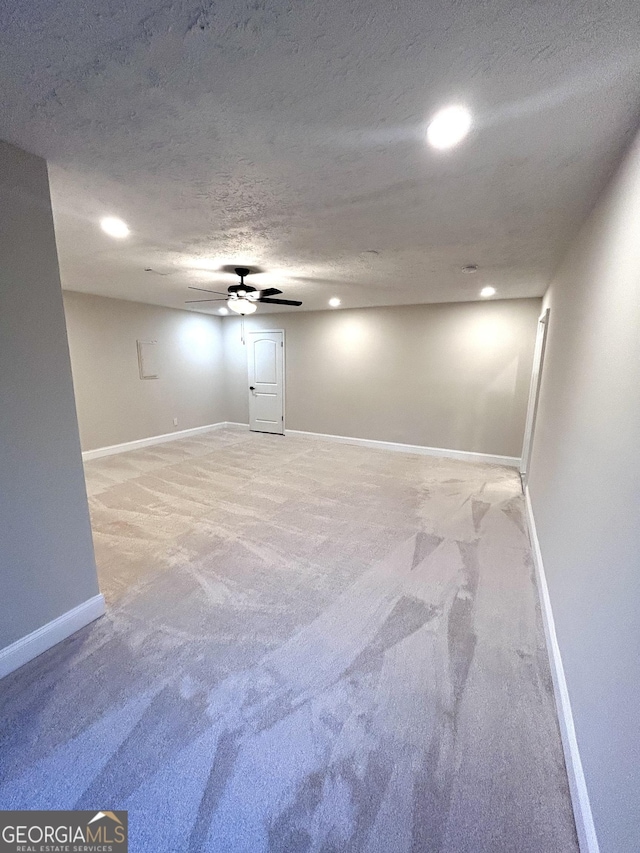 basement featuring light colored carpet and a textured ceiling