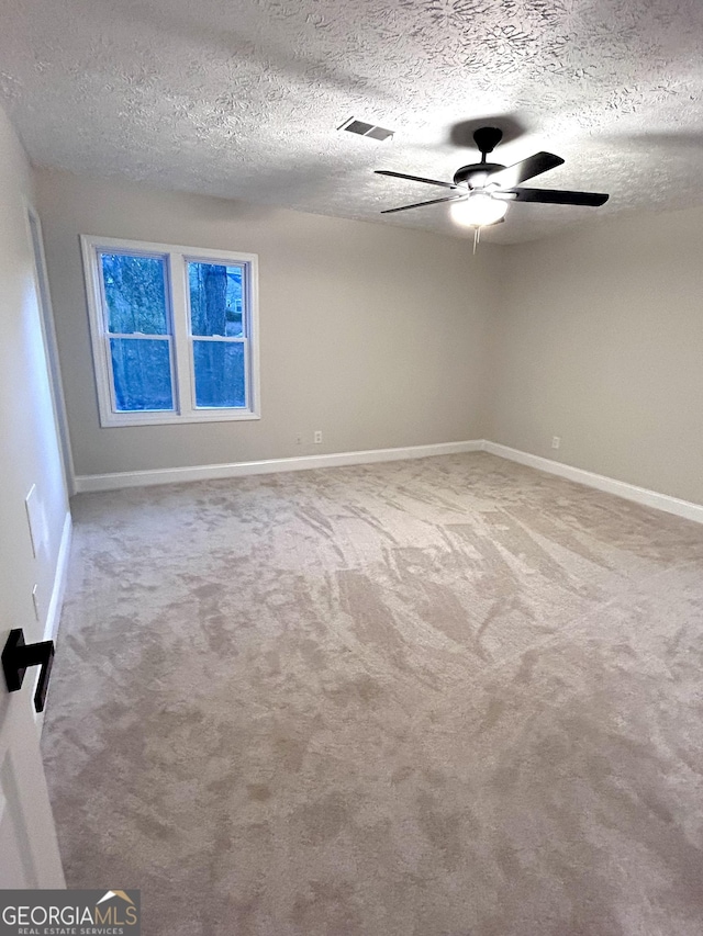 carpeted spare room with ceiling fan and a textured ceiling