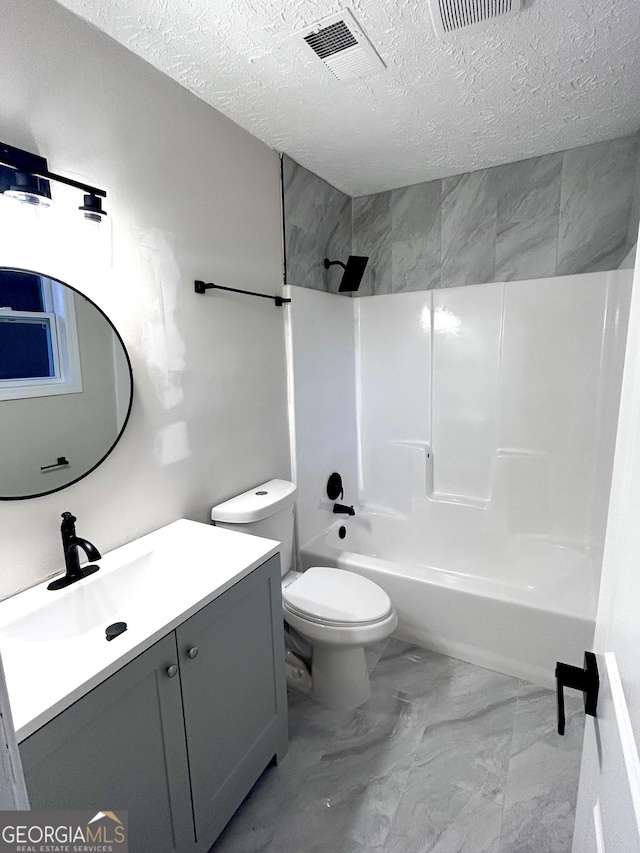 full bathroom with vanity, a textured ceiling, tiled shower / bath combo, and toilet