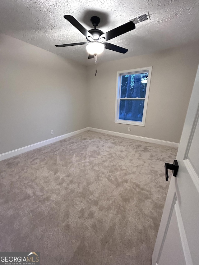 empty room featuring ceiling fan, carpet floors, and a textured ceiling