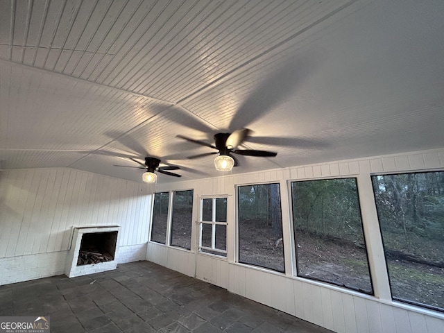 unfurnished sunroom with a healthy amount of sunlight, a brick fireplace, ceiling fan, and lofted ceiling