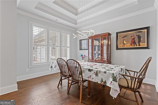 dining room with dark hardwood / wood-style floors, a raised ceiling, and an inviting chandelier