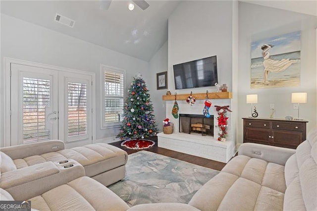 living room with hardwood / wood-style flooring, ceiling fan, a fireplace, and high vaulted ceiling