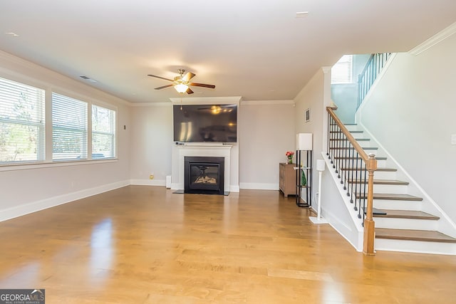 unfurnished living room with light wood-type flooring, ceiling fan, and ornamental molding