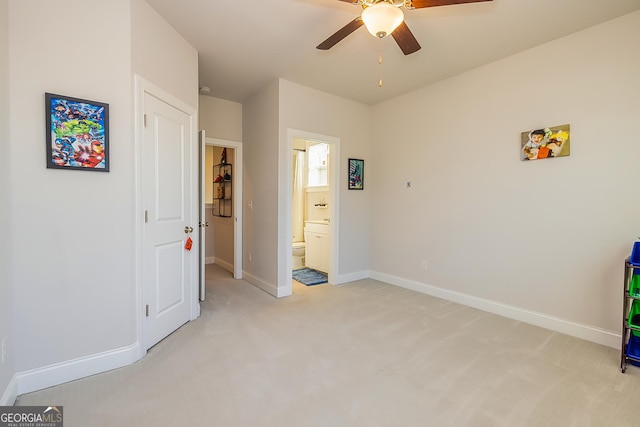 unfurnished bedroom featuring ceiling fan, light carpet, and ensuite bath