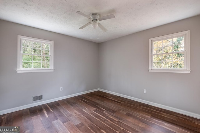 spare room with baseboards, dark wood-style flooring, ceiling fan, and visible vents