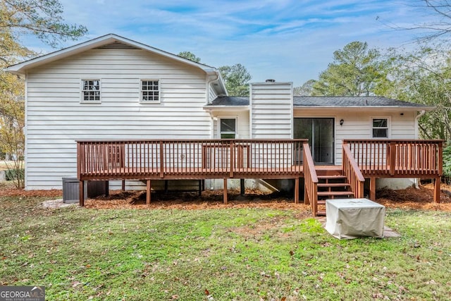 rear view of property featuring a lawn, a chimney, and a wooden deck