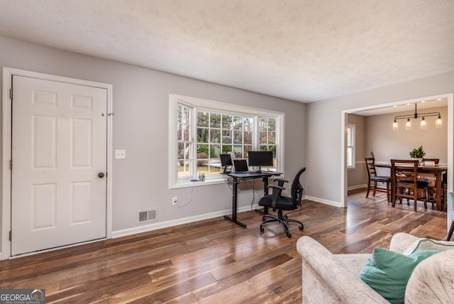 home office featuring a textured ceiling, visible vents, baseboards, and hardwood / wood-style floors