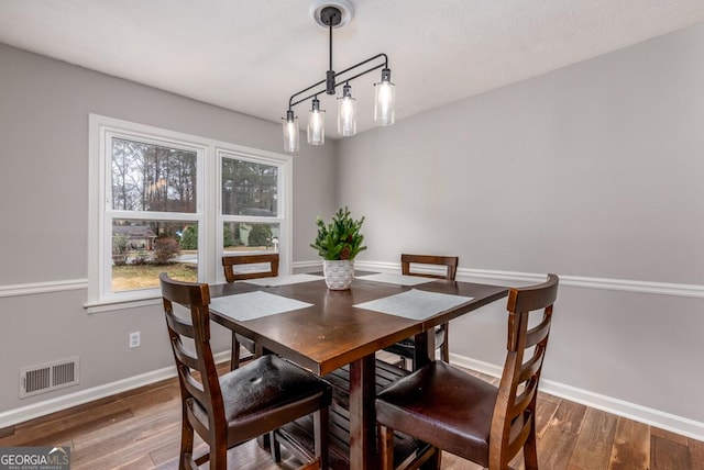 dining area with baseboards, visible vents, and wood finished floors
