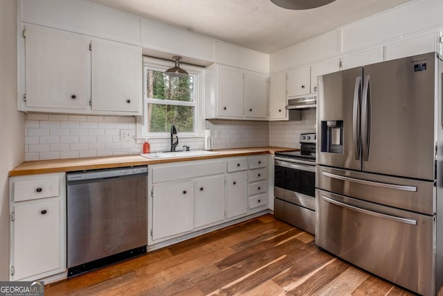 kitchen featuring stainless steel appliances, dark wood-type flooring, under cabinet range hood, white cabinetry, and a sink
