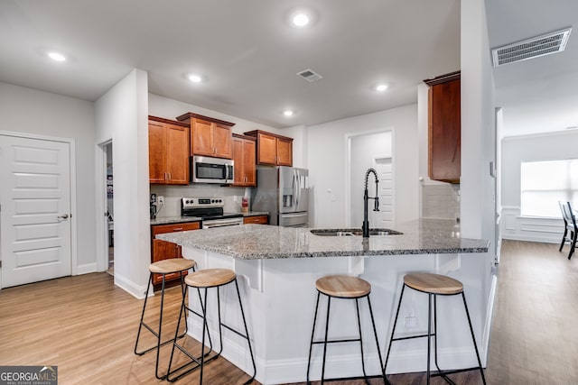 kitchen featuring light stone countertops, appliances with stainless steel finishes, a breakfast bar area, and kitchen peninsula