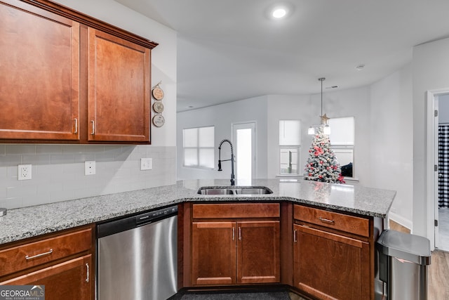 kitchen featuring sink, decorative backsplash, stainless steel dishwasher, kitchen peninsula, and light stone countertops