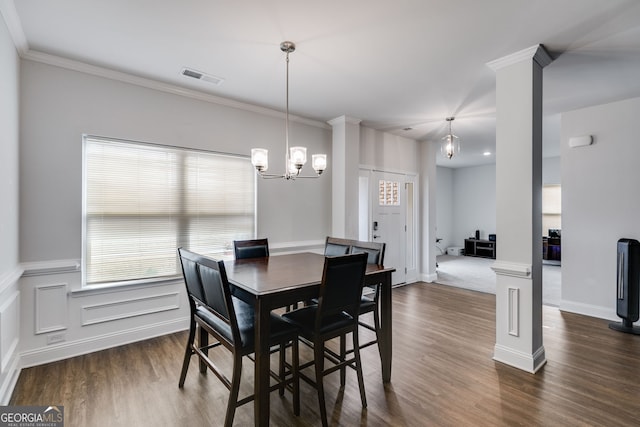 dining space with crown molding, dark hardwood / wood-style floors, a chandelier, and ornate columns