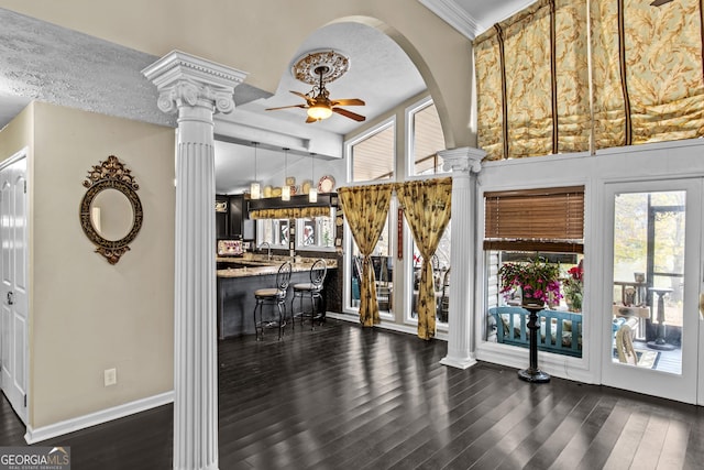 interior space featuring ceiling fan, sink, dark wood-type flooring, decorative columns, and a textured ceiling