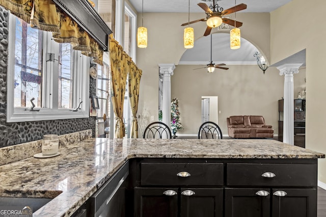 kitchen featuring light stone countertops, stainless steel dishwasher, ornate columns, and ornamental molding