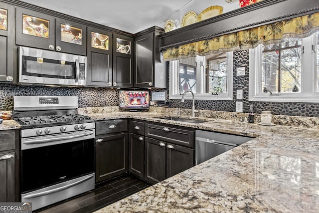 kitchen featuring light stone countertops, sink, stainless steel appliances, dark hardwood / wood-style flooring, and decorative backsplash