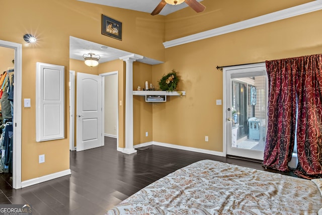 bedroom with a walk in closet, decorative columns, access to outside, ceiling fan, and dark wood-type flooring