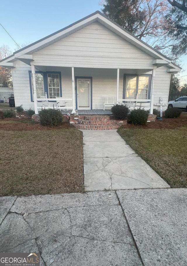 bungalow featuring a porch and a front lawn