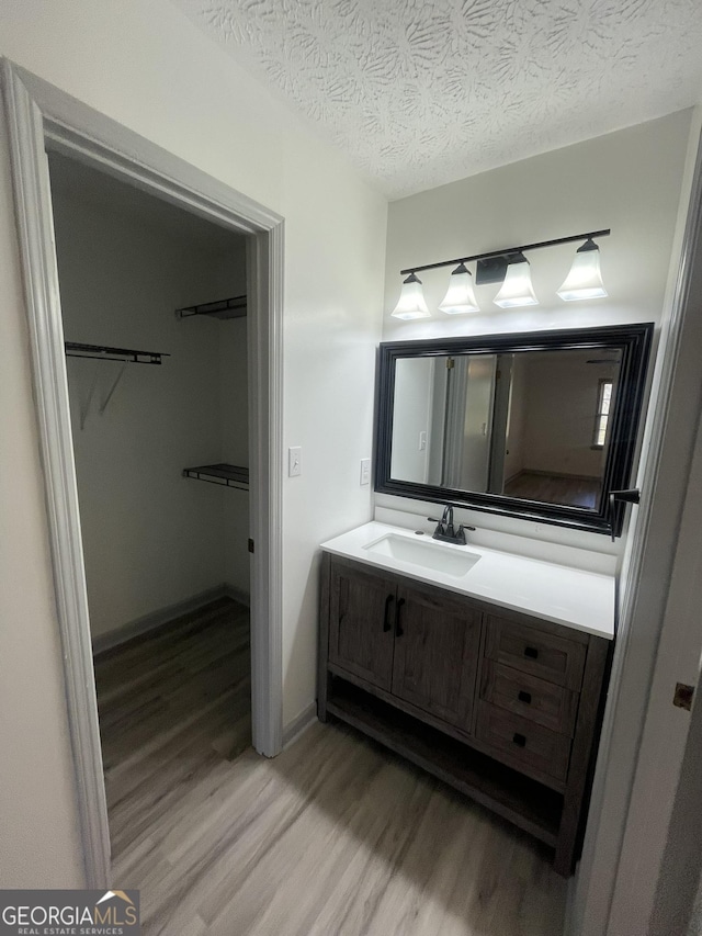 bathroom with wood-type flooring, a textured ceiling, and vanity