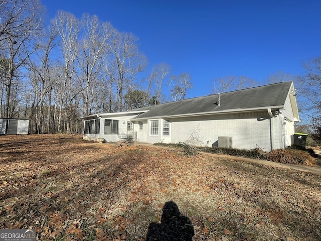 rear view of property with central air condition unit and a sunroom