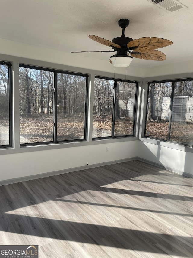 unfurnished sunroom with ceiling fan