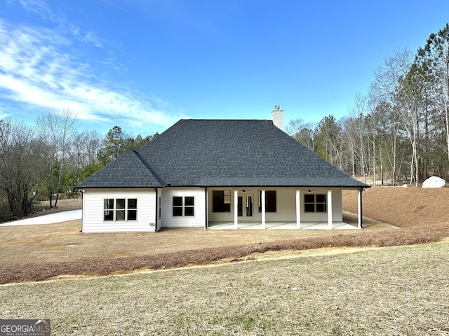 rear view of house featuring a ceiling fan, a patio area, a shingled roof, and a chimney